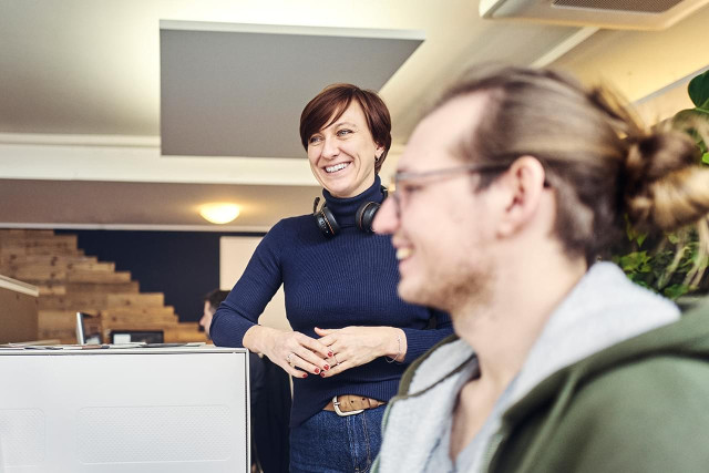 Kolleg:innen im DOTS-Büro bei einem lockeren Austausch. Die Szene zeigt eine kreative Arbeitsatmosphäre und das positive Teamgefühl in der Freiburger Agentur.